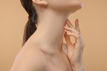 Obraz na płótnie Canvas Woman touching her neck on beige background, closeup