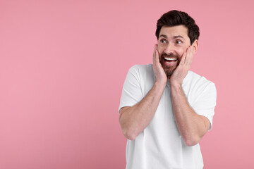 Portrait of happy surprised man on pink background, space for text