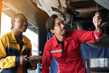 Male and female mechanic working at garage. Professional mechanics checks, repair and maintenance...
