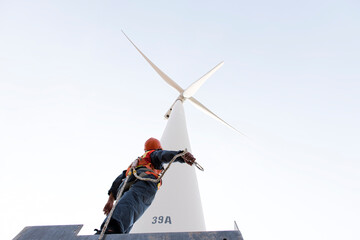  Maintenance engineer standing  against turbines on wind turbine farm. © ENGINEER - STUDIO