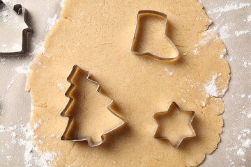 Making Christmas cookies. Raw dough and metal cutters on parchment paper, flat lay