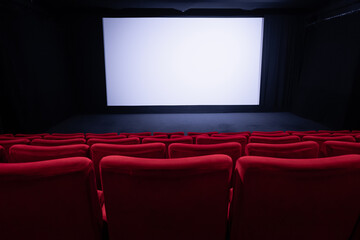 Cinema blank wide screen and empty red chairs