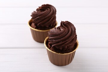Delicious chocolate cupcakes on white wooden table