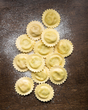 Uncooked homemade ravioli on an old wooden table, top view
