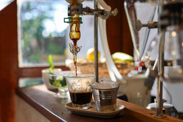 selective focus black coffee in a clear glass 1 shot obtained from liquid distillation equipment In...