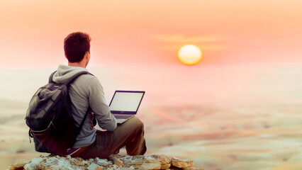 A person sitting with a laptop in a remote natural setting as the sun sets, highlighting the concept of remote work and freedom. - obrazy, fototapety, plakaty