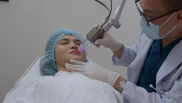 Side view of asian woman getting resurfacing laser fraxel dual and ultrasound face treatment in medical spa center. skin rejuvenation concept	