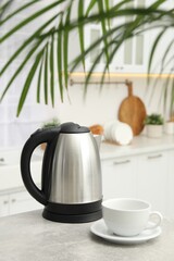 Electric kettle and cup on table in kitchen