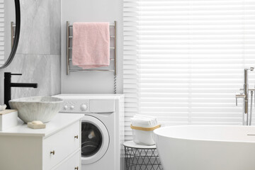 Stylish bathroom interior with heated towel rail and modern white tub