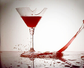 Red wine splashes flowing into a broken glass