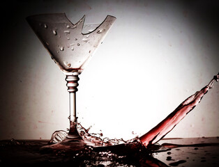 Red wine splashes flowing into a broken glass