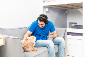 Positive guy sits on the couch and plays with his cute dog	