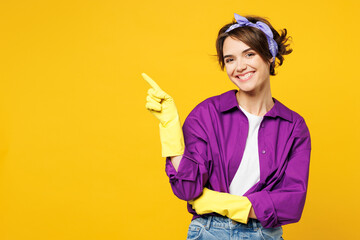 Young smiling happy woman she wear purple shirt rubber gloves while doing housework tidy up point...