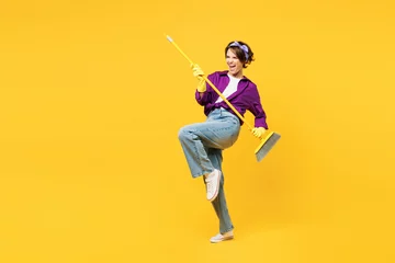 Fotobehang Full body young happy woman wears purple shirt casual clothes do housework tidy up hold in hand brush broom pov play guitar isolated on plain yellow background studio portrait. Housekeeping concept. © ViDi Studio