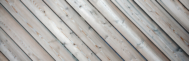 Old planks create a diagonal pattern of natural pine texture. Weathered boards with a diagonal pattern. The tree darkened under the sun. Clear tree structure in the sun