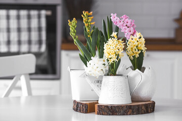Spring hyacinth flowers on a white table. In the background is a white Scandinavian-style kitchen....