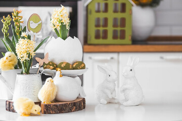 Happy Easter. Spring yellow hyacinth flowers in an egg-shaped vase, chicken chicks on a white table. In the background is a white Scandinavian-style kitchen. Easter decor in the house.