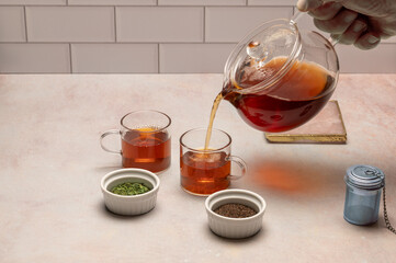 Pouring tea from pitcher with loose leaf tea in foreground 