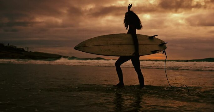 Woman, silhouette and walking with surfboard on beach at night for waves, sport or outdoor surfing in nature. Female person or surfer on ocean coast in late evening for surfing, holiday or weekend