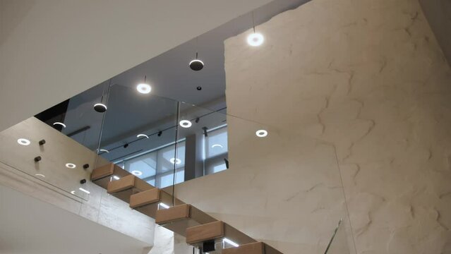 Wooden staircase with glass railing and chandelier in the building