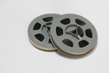 Two reels of old 8mm film stacked on each other against a white background. 