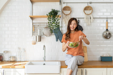 Portrait of beauty body slim healthy asian woman eating vegan food healthy with fresh vegetable salad in kitchen at home.diet, vegetarian, fruit, wellness, health, green food.Fitness and healthy food - obrazy, fototapety, plakaty
