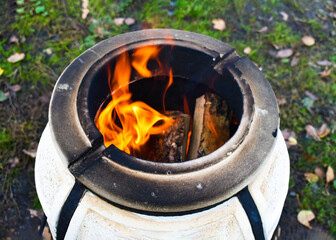 Portable clay tandoor oven with burning fire inside for cooking barbecue outdoors