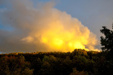 Big cloud in the evening light over green forest