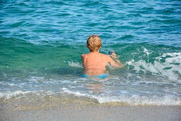 Boy sitting in the water on the sandy beach
