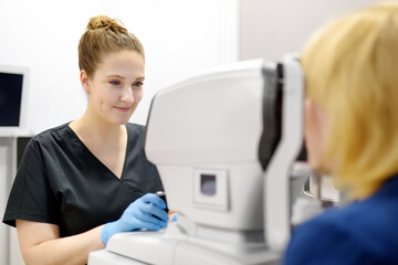 Examining of fundus of mature woman by female ophthalmologist using retinal scanner. Patient during...