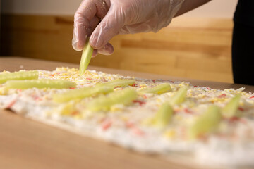 Stuffing and cucumber are added to the unfolded pita bread. Preparation of pita bread roll.