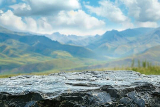 An irregular Dark Stone slab at the bottom of the image, rolling mountains in the distance, blue sky, white clouds, bokeh in the background, front view, high resolution stock photo, closeup view.