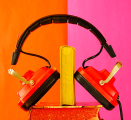 audiobooks concept with books and vintage headphones.Bright red and pink background with large copy space - 760660485