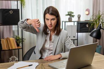 Dislike. Upset Caucasian businesswoman working on laptop computer at office showing thumbs down...