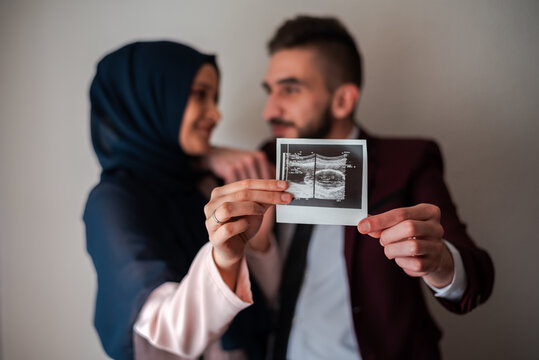 Gender Reveal Concept. Happy pregnant muslim couple holding holding baby ultrasound photo