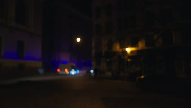 A police car with electric blue lights driving on a dark city road at midnight