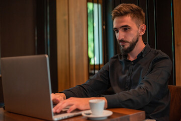 Young business man working on a laptop at office or cafe restaurant.