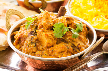 Traditional Indian chicken curry served with spices and chicken pieces as close-up in a kadai bowl