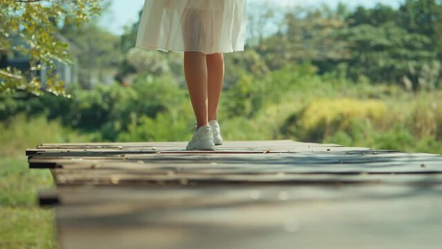 B roll - Rear view of Woman legs wearing sneakers walking on wooden bridge with trees background, Vacation and traveling concept