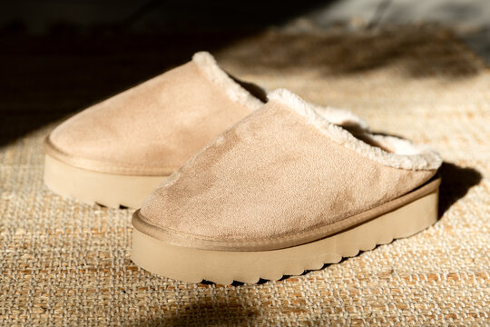 A pair of Uggs slippers on a jute rug.