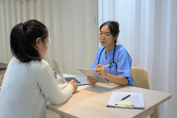 A woman is sitting at a desk with a laptop and tablet in front of her