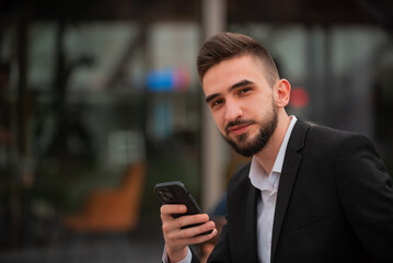 A young happy business man using a phone mobile outdoor near the office buliding.