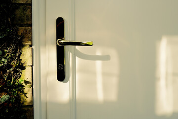 Isolated view of a newly installed garage door showing the ornate brass effect handle. The door leads to the side entrance of a single garage.