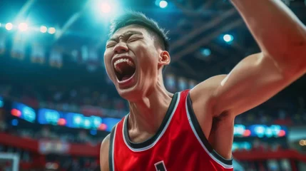 Fotobehang Asian basketball player celebrates victory, unleashing shouts of joy against the backdrop of a basketball stadium. Emotional celebration of winning the game © Vladimir
