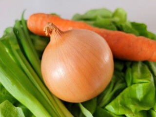 Yellow onion, raw carrot and lettuce leaves for healthier eating.