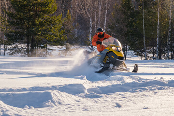 Athlete on a snowmobile moving in the winter forest in the mountains of the Southern Urals
