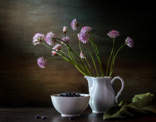Modern still life with a bouquet of blooming onions and honeysuckle on a dark background