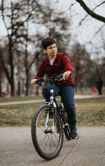 A young boy rides his bicycle through a city park, exemplifying healthy, active outdoor living and the freedom of youth.