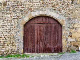 Old large vaulted wooden door on a vintage stone wall
