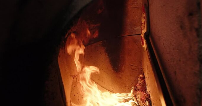 Traditional Italian pizza preparation. Pizzaiolo puts pizza in a wood fired oven at restaurant. Chef cooks pizza in firewood stone oven with flame. Vertical shot